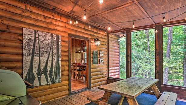 Interior rústico de una cabaña de madera con una mesa, bancos y comedor.