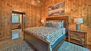 Un dormitorio con paneles de madera, una cama grande, una mesita de noche, una lámpara y un cuadro en la pared.