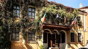 Um edifício histórico com janelas em arco, fachada de pedra e um pátio de paralelepípedos.