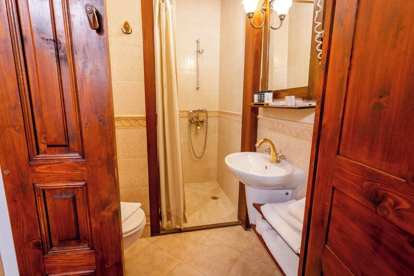 A wooden bathroom with a toilet, a shower, and a sink.