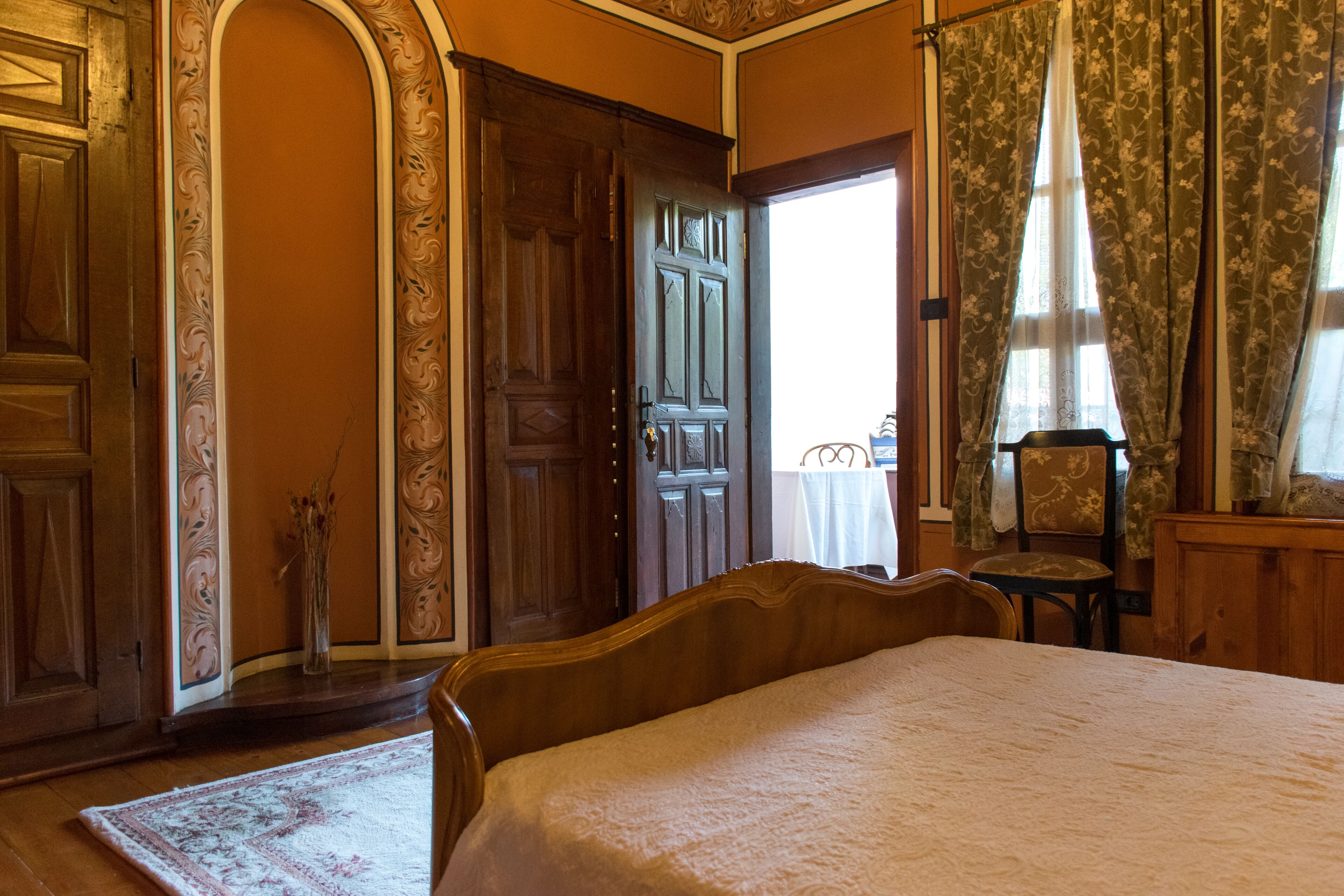 Quarto com cama grande, guarda-roupa de madeira e uma cadeira.