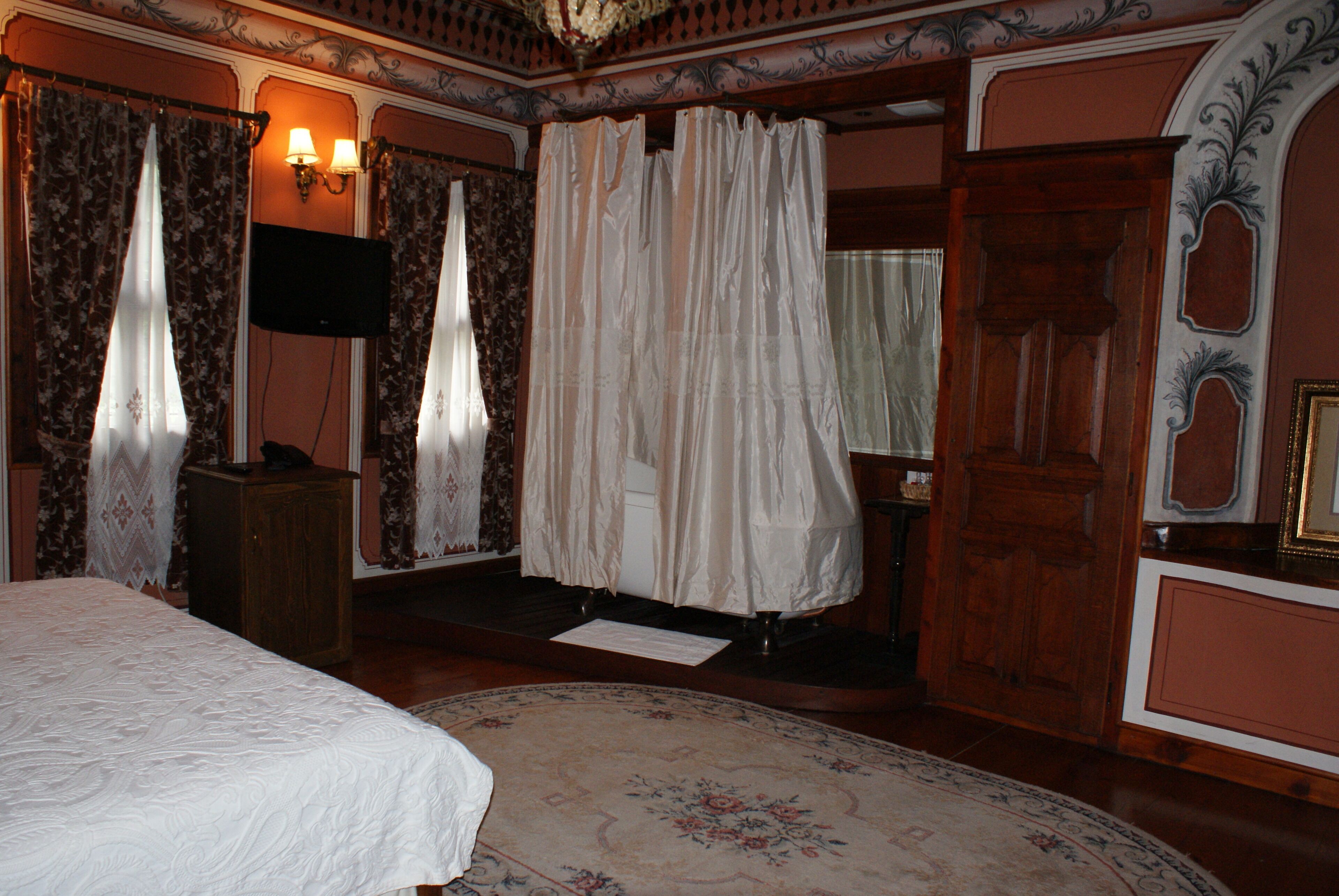 Ein Zimmer mit einem Bett, einem Flachbildfernseher, einem Holzschrank und einem großen Teppich mit Blumenmuster.