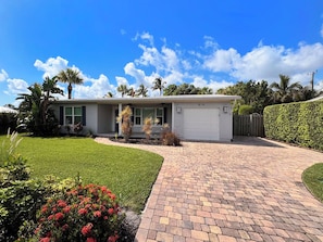 A single-story house with a garage, surrounded by a well-maintained lawn and a brick driveway.