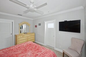 A bedroom with a bed, dresser, chair, ceiling fan, and a TV. - Peaceful Paradise Oasis (Stuart)
