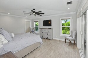 A bedroom with a bed, a dresser, a chair, a ceiling fan, and a TV. - Peaceful Paradise Oasis (Stuart)