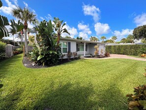 A residential property with a well-maintained lawn, a house with a porch, and tropical plants. - Peaceful Paradise Oasis (Stuart)