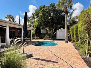 A backyard with a swimming pool, a covered patio, and a shed. - Peaceful Paradise Oasis (Stuart)