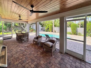 A covered patio with a pool, outdoor furniture, and a view of the backyard. - Peaceful Paradise Oasis (Stuart)