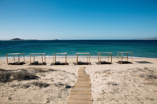 En la playa, playa de arena blanca, camastros y sombrillas 
