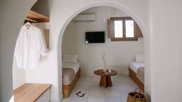 A minimalist room with a bed, a TV, a small table, and a bench.