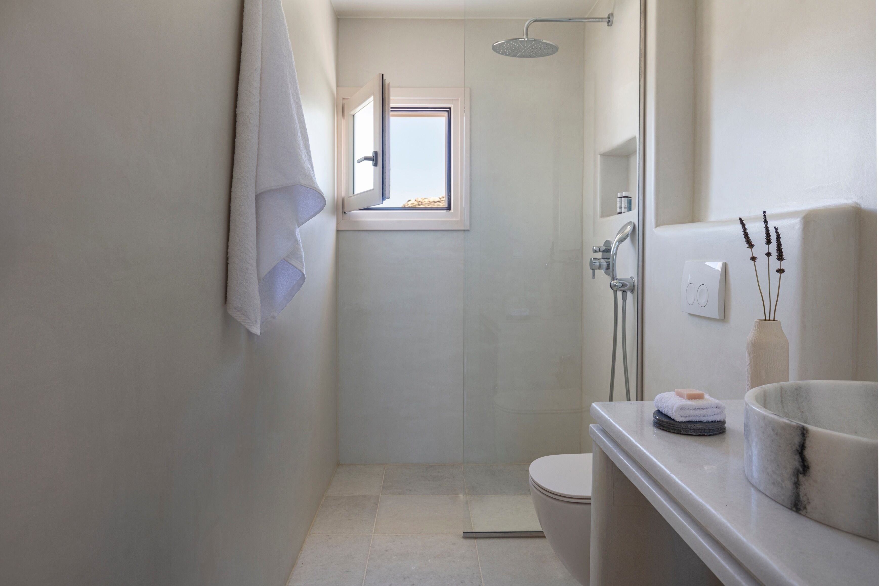 A modern bathroom with a shower, toilet, and a sink with a marble basin.