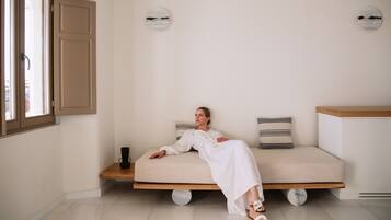 Relax in a serene space with a comfortable bed and natural light pouring in through the large window.