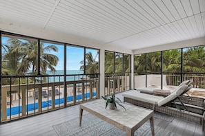 A spacious balcony with a view of a swimming pool and palm trees.