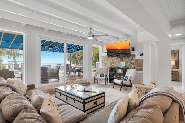 A spacious living area with a large TV, comfortable seating, and a view of the ocean.