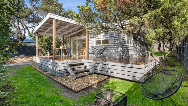 Una casa moderna con un porche cubierto, una pequeña terraza y un jardín.