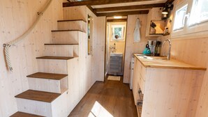 A wooden interior with a staircase, a kitchen area, and a small bathroom. - Tiny house on the alpaca farm - Tiny House (Rubkow)