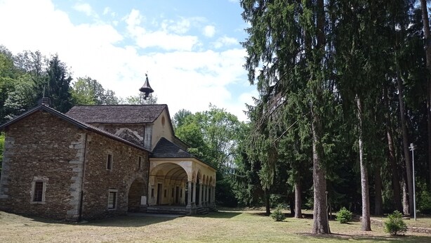 A stone building with a covered courtyard and tall trees. - House at Nonna Pina's at the gateway to the Val Grande (Cossogno)