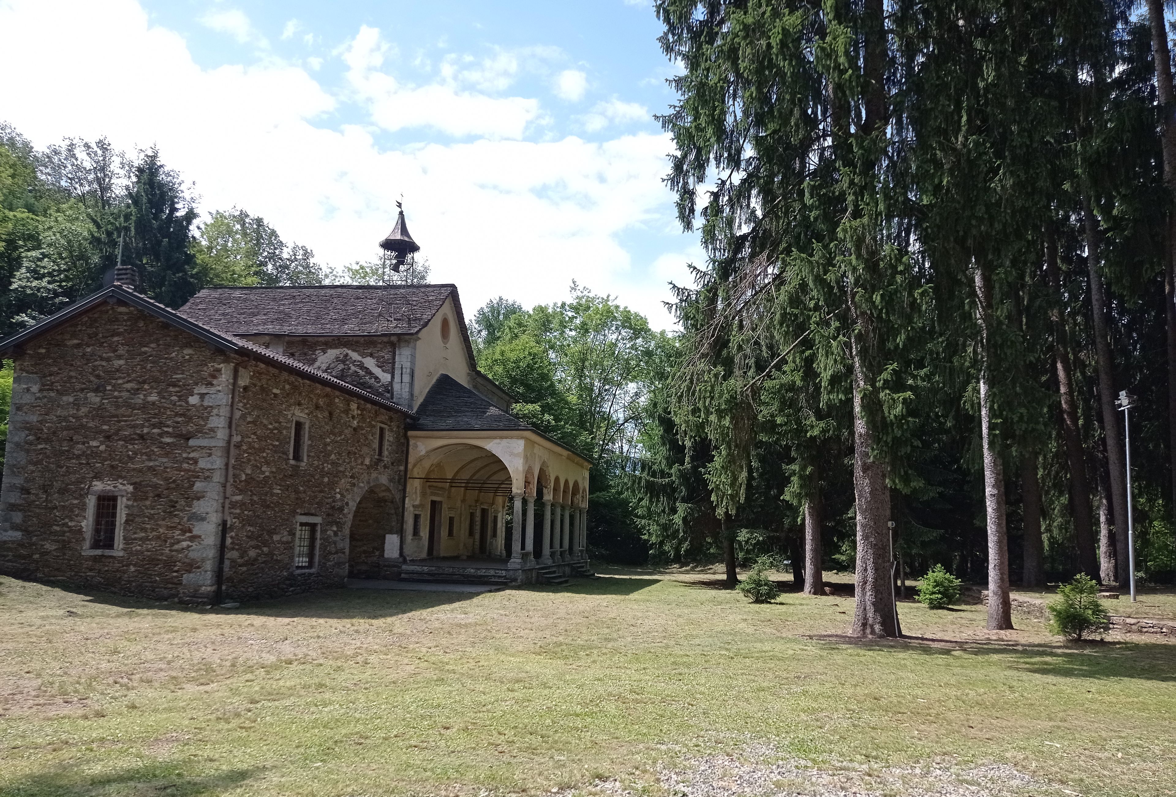 A stone building with a covered courtyard and tall trees.