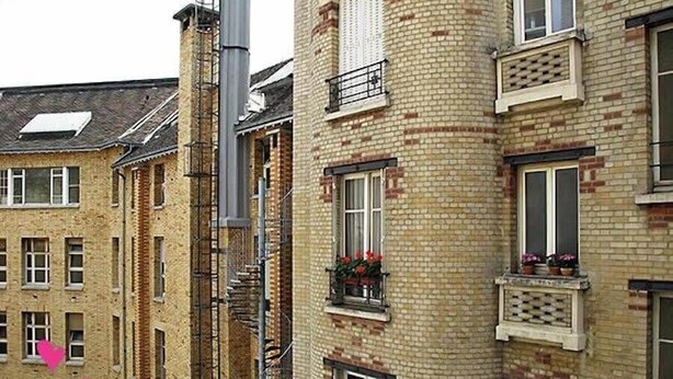 Ein mehrgeschossiges Gebäude mit Backsteinfassaden, zahlreichen Fenstern und einer sichtbaren Treppe.