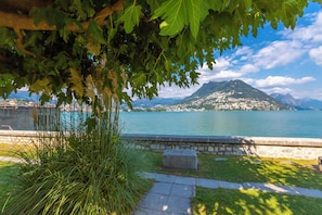 Escape to a serene lakeside haven with a mountain backdrop, where a peaceful pathway leads to a grassy area with a bench for relaxation.