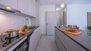 A modern kitchen with a stove, oven, and countertop with food items. - Coloratura Frontlake Lugano With Terrace (Paradiso)