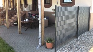 Een overdekt buitengebied met een houten pergola, een tafel met stoelen en een bloempot.