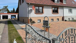 Een huis met twee verdiepingen, een rode pannendak, een garage en een geplaveid pad.