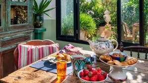 A wooden table with breakfast items, a teapot, and a bowl of strawberries. - Hiraeth: Stylish canava house with pool and garden (Μεγαλοχώρι)