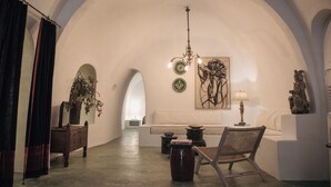 A room with a high arched ceiling, a sofa, a chair, a table, a lamp, and a chandelier. - Hiraeth: Stylish canava house with pool and garden (Μεγαλοχώρι)