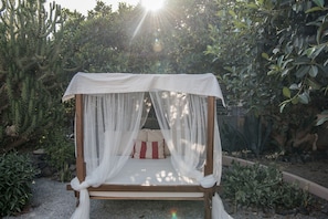 A garden bed with a white canopy bed. - Hiraeth: Stylish canava house with pool and garden (Μεγαλοχώρι)