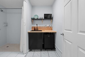 A compact kitchen with a microwave, sink, and storage cabinets.