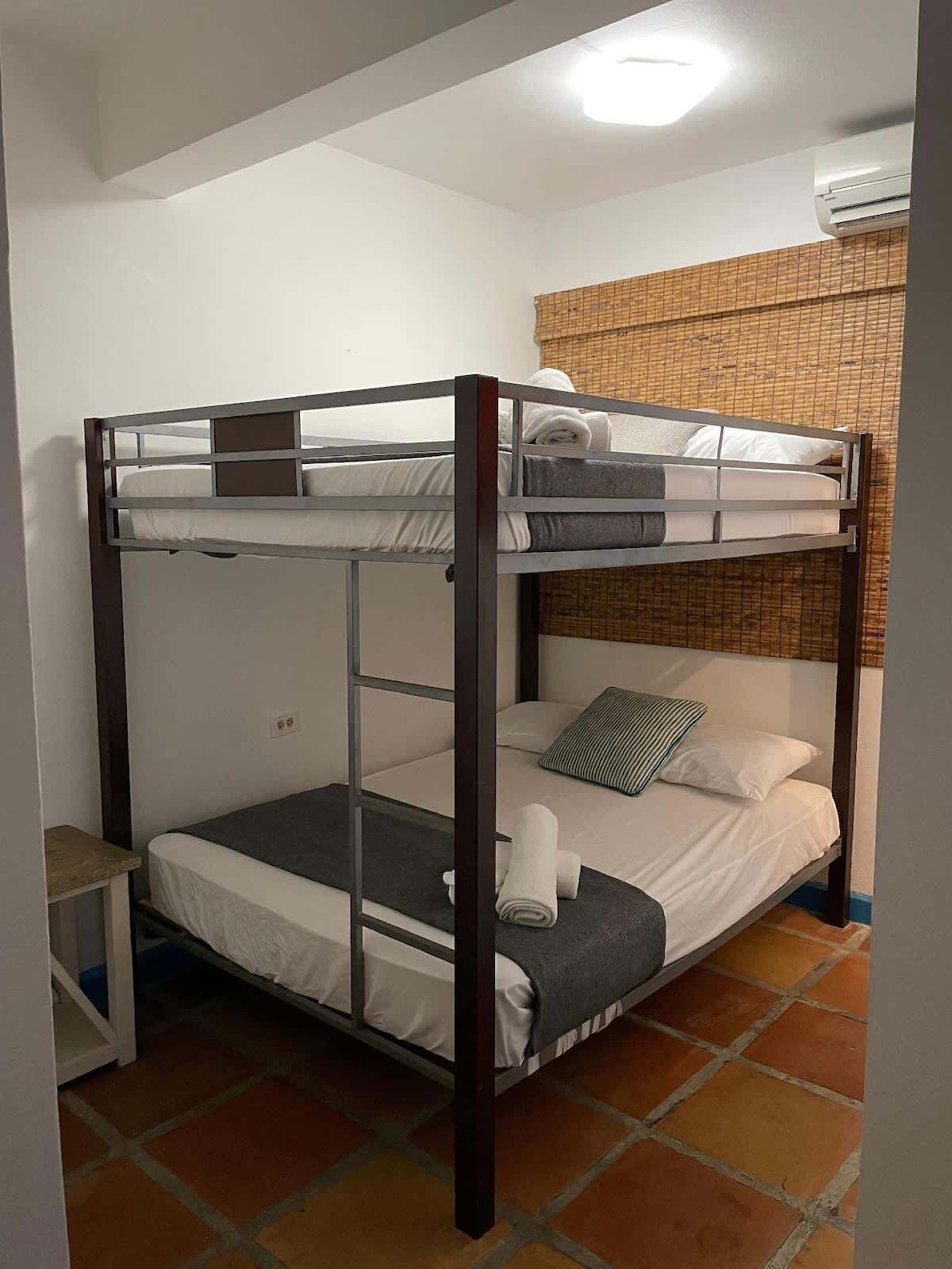 A bunk bed room with a small table and a wall-mounted air conditioner.