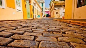 A cobblestone street leading to a building with a green door. - Condado Beach Stay | 3BR | Wi-Fi | Great Location (San Juan)