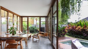 A spacious indoor area with a dining table, chairs, and a pool area.