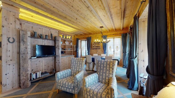 Un intérieur chaleureux en bois, avec un téléviseur, des chaises à motifs et un coin repas.