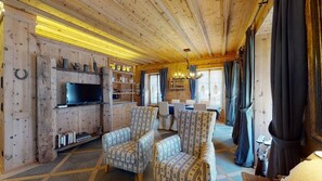 Un interior acogedor de madera con televisión, sillas estampadas y un comedor.