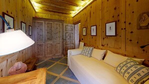 Une pièce en bois avec un lit, un bureau et une chaise. Des tableaux encadrés ornent les murs.