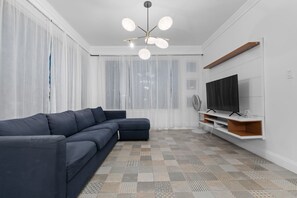 A modern living room with a sectional sofa, a flat-screen TV, a pendant light, and patterned flooring. - 1954 Modern Apartment | San Juan | Wi-Fi | AC (San Juan)