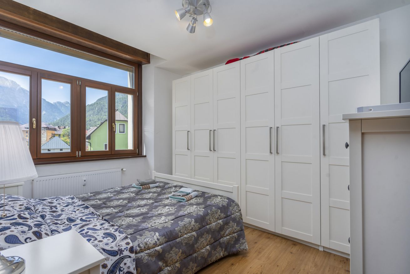 Ein Schlafzimmer mit Bett, einem Fenster mit Bergblick und einem Kleiderschrank.