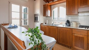 A kitchen with wooden cabinets, a white countertop, a stove, and a window. - GuestHost - San Marco Apartment with Panoramic View (Firenze)