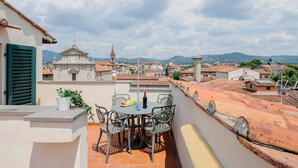 A rooftop terrace with a table and chairs, a potted plant, and a bottle of wine. - GuestHost - San Marco Apartment with Panoramic View (Firenze)