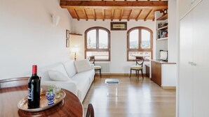A modern interior with a dining area, white sofa, wooden ceiling, and large windows. - GuestHost - San Marco Apartment with Panoramic View (Firenze)