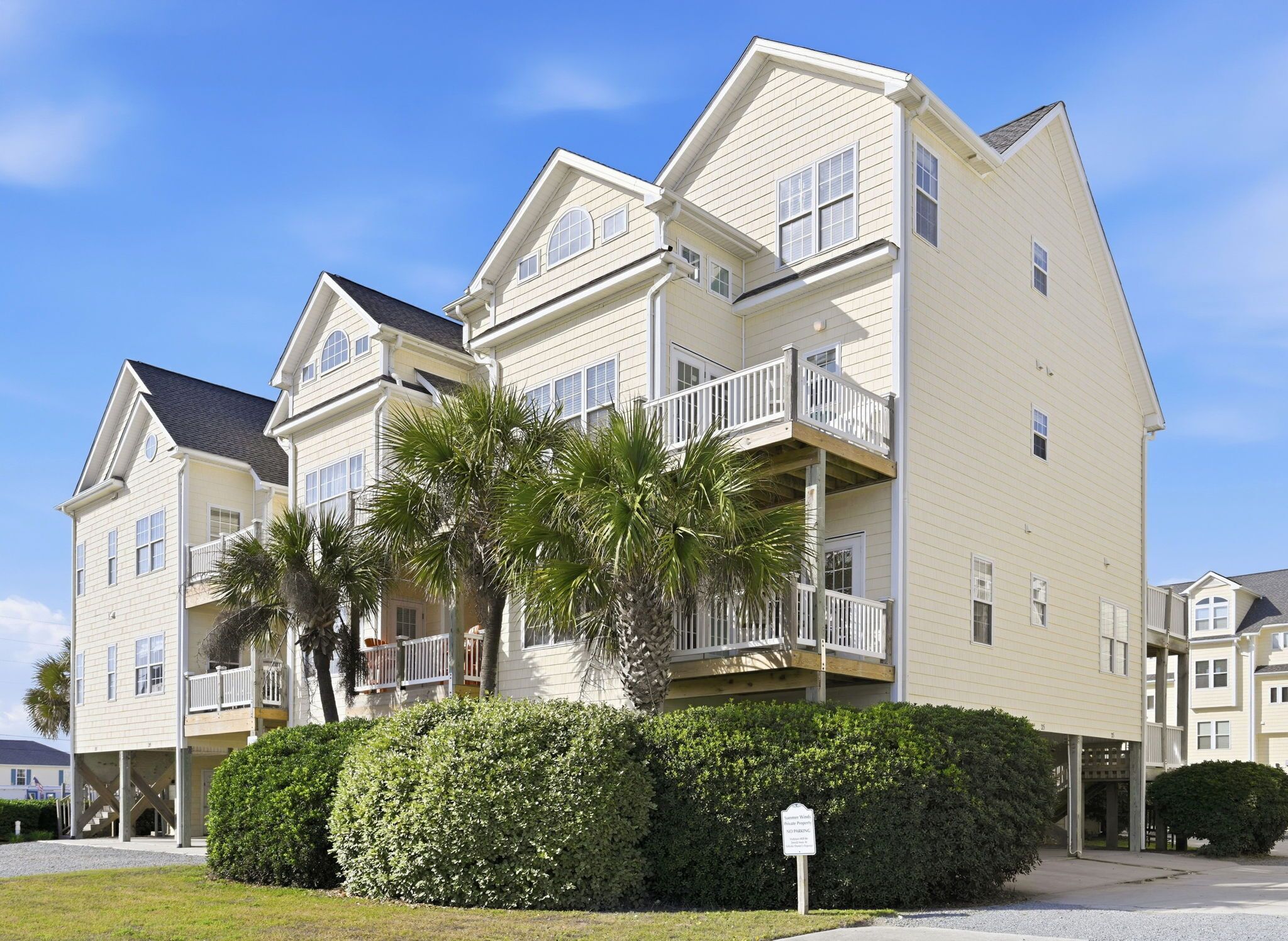 A multi-story residential building with balconies, a covered entryway, and a no parking sign.