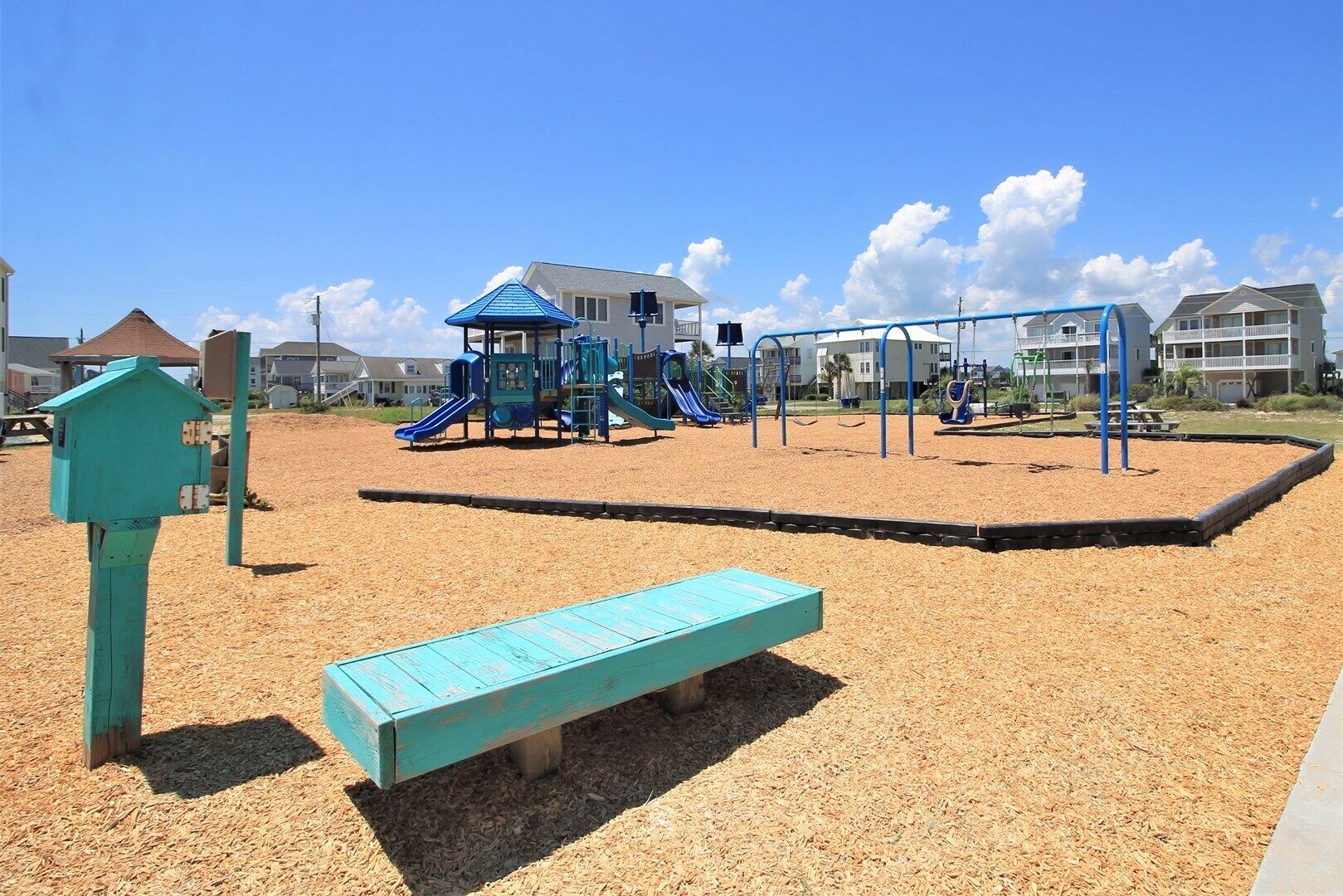 Ein Spielplatz mit Rutschen, Schaukeln, einer Bank und einem Gebäude im Hintergrund.