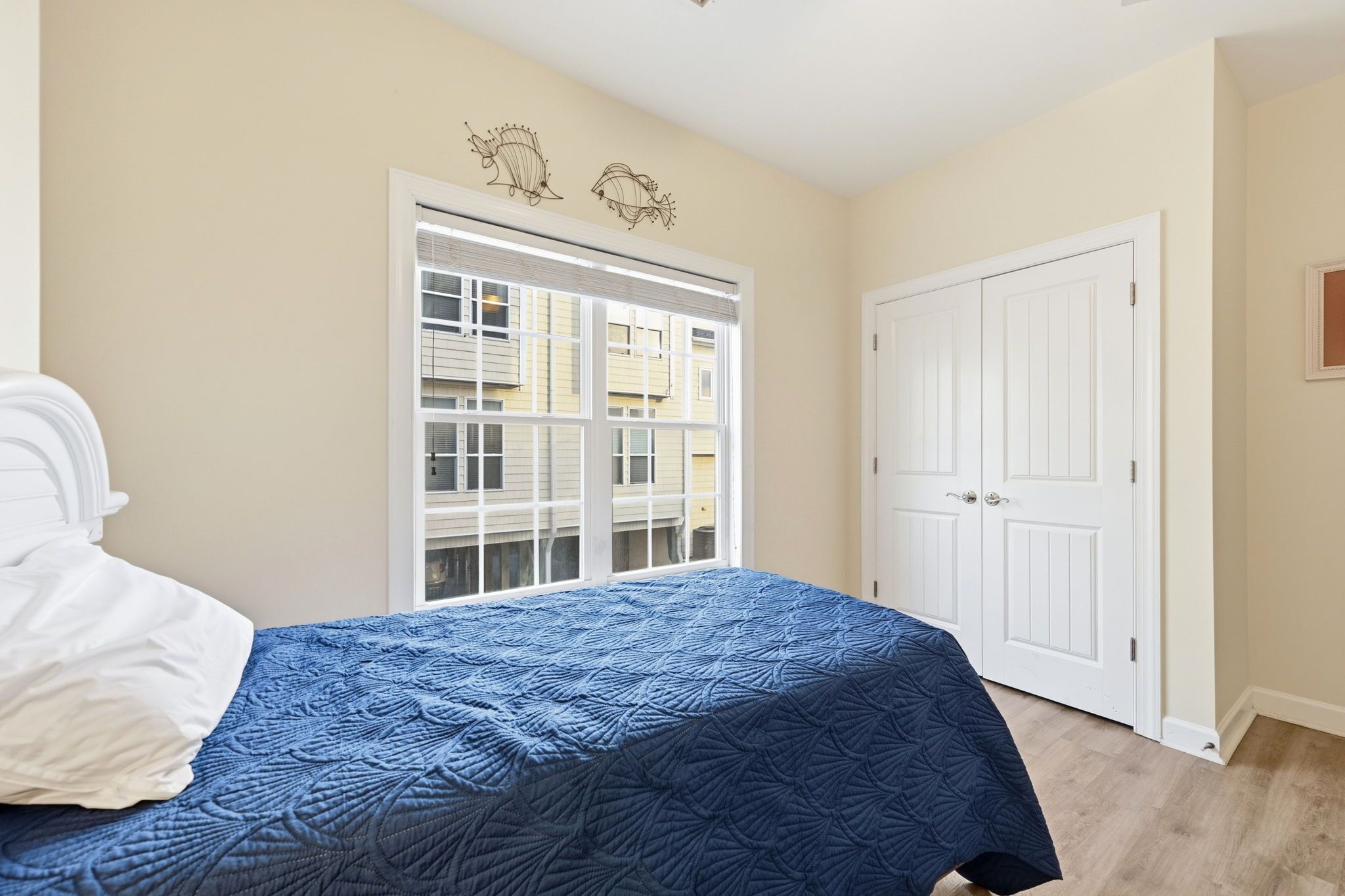 A bedroom with a bed, a window, a door, and a wall decoration.