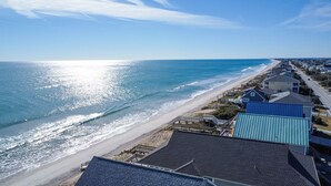 A coastal residential area with houses along the beach, a clear sky, and a bright sun reflecting on the water. - Sandy Paradise: An oceanfront, 6-bedroom retreat in Surf City, perfect for 20 guests! (Surf City)