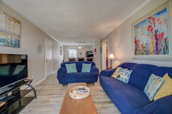 A living room with a television, two sofas, a coffee table, and a painting on the wall.