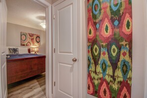 A bedroom with a bed, a dresser, and a wall with a colorful abstract painting. - Enjoy oceanfront views in this cute 2-bedroom condo at North Topsail Beach. (North Topsail Beach)