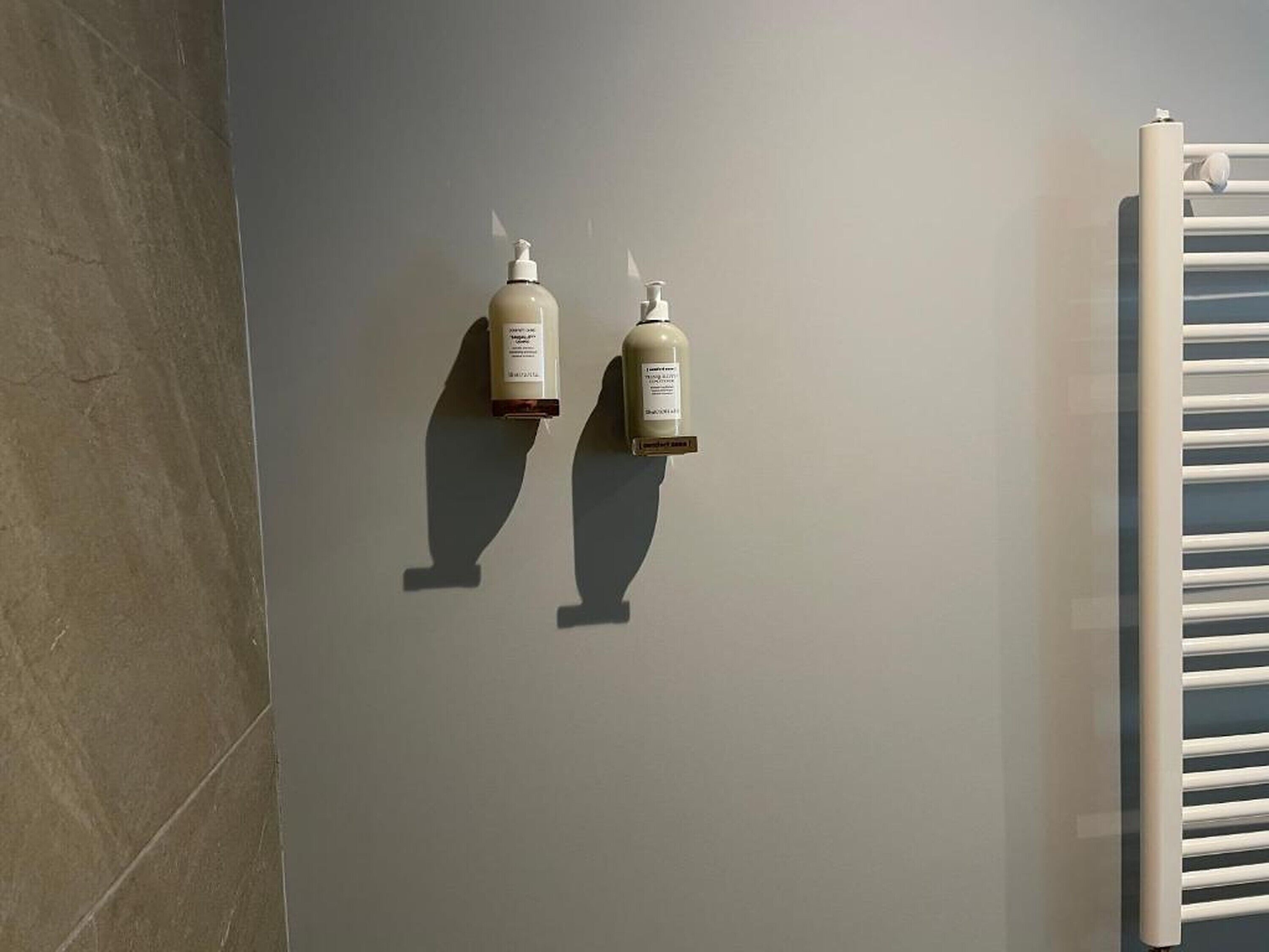 Dos botellas de champú y acondicionador sobre una pared.