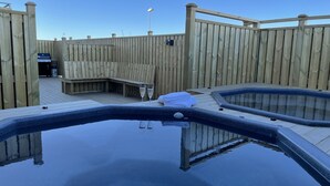 A wooden deck with a hot tub and a barbecue grill.